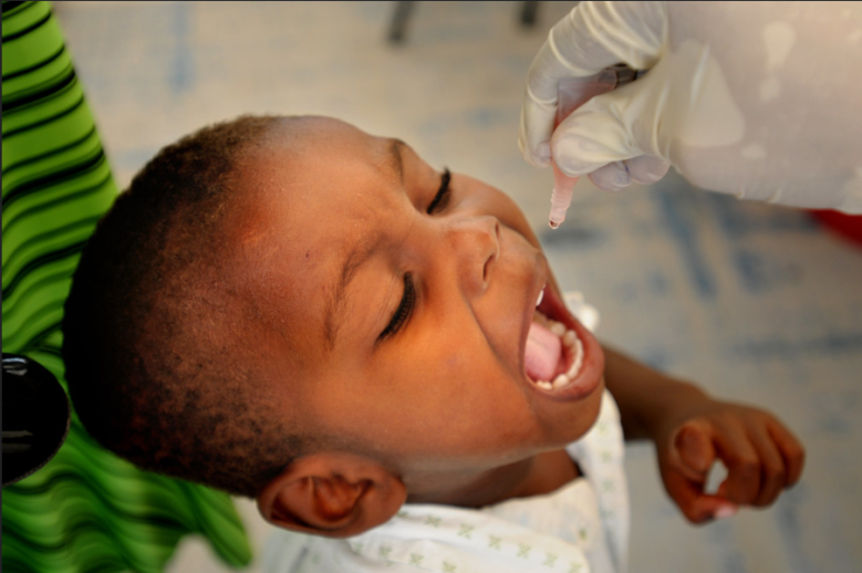 Nuori musta poika saa pipetillä annosteltavan poliorokotuksen Haitin Port-au-Princessä